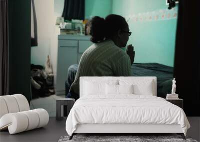 One hispanic older woman praying by the bedside. Religious elder person in FAITH prayer Wall mural