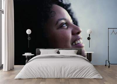 One hopeful meditative young black woman with eyes closed in contemplation. Faithful female person opening eye to sky smiling Wall mural