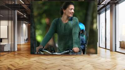 Parent riding bicycle with little boy in bike back seat mother rides with child Wall mural