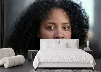 Portrait face of a young black woman looking at camera. A hispanic South American Brazilian adult girl with curly hair with natural expression Wall mural