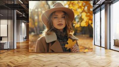 portrait of a warm woman taking a yellow leaf in autumn Wall mural