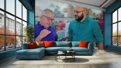 Senior manager of grocery store speaking with staff while looking at tablet device. Two men standing inside local business, job occupation delegation concept Wall mural