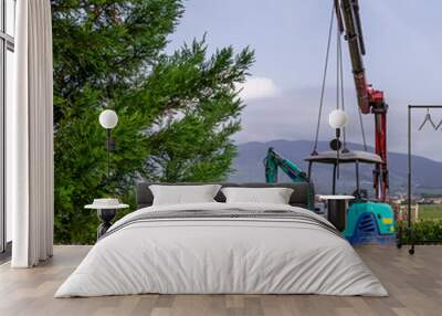 A mini excavator is lifted into the air to be transported on a crane truck Wall mural