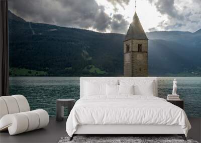 The sun peeps out from the top of the old bell tower of Curon Venosta, submerged in Lake Resia, South Tyrol, Italy Wall mural