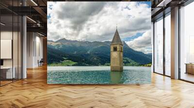 The top of the old bell tower of Curon (Graun) emerges from the waters of Lake Resia, against a dramatic sky, South Tyrol, Italy Wall mural