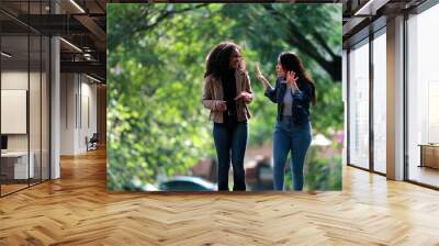 Two diverse young women laughing together while walking outside in street Wall mural