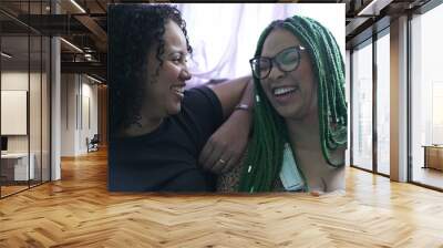 Two young black women laughing together. Hispanic latin women real life laugh and smile Wall mural