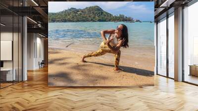 Asian Thai woman practicing yoga at evening in Haad Chaloklum beach, Koh Phangan island, Thailand. Revolved crescent lunge pose Wall mural