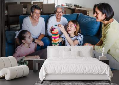 Hispanic family playing Jenga game with grandmother and daughter at home, three generations of women in Mexico Latin America Wall mural