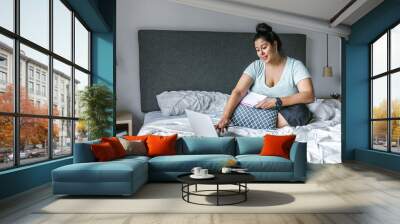 Plus size latin girl working on laptop in bedroom in Latin America, plus size woman Wall mural