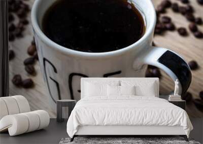 Cup of coffee with beans on wooden table Wall mural