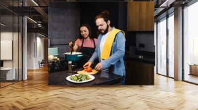 Young latin couple cooking dinner together in kitchen in home at night in Mexico Latin America, hispanic people Wall mural