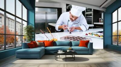 young latin man chocolatier in chef hat standing with mexican chocolates candies on plate in a commercial kitchen in Mexico Latin America Wall mural