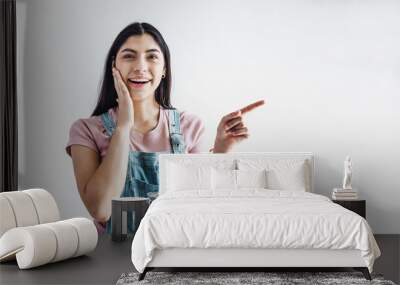 young latin woman pointing at copy space looks in camera in Latin America Wall mural