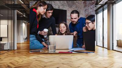 Young latin woman working with computer and her coworkers at the office or coworking in Mexico or South America, Mexican teamwork Wall mural