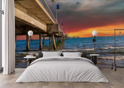 a gorgeous summer landscape at the Belmont Veterans Memorial Pier with blue ocean water and waves rolling into the beach and curved light posts along the beach with powerful clouds at sunset Wall mural