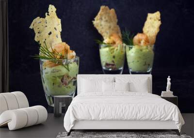 avocado cream or guacamole with shrimps and cheese crisp in a glass, appetizer or party snack on a dark slate background with copy space Wall mural