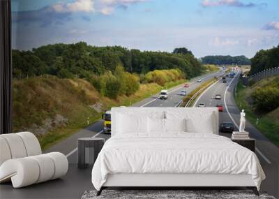 Cars and trucks are driving on the highway through a country landscape, transport and environment concept, blue sky with clouds and copy space Wall mural