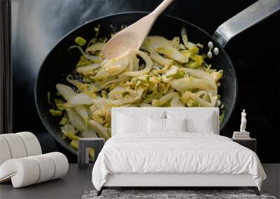 Fennel slices and leek in a black frying pan on the stove, cooking vegetarian with healthy vegetables Wall mural