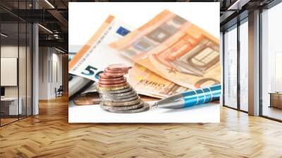 financial planning with coins and euro banknotes, a calculator and a pen isolated on a white background, panoramic banner format Wall mural