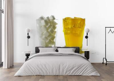 glass full of sugar cubes compared to a glass with a yellow sweet beverage, isolated on a white background Wall mural