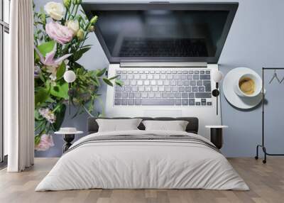 Silver colored laptop on a gray desk with a bouquet of flowers and a coffee cup, business workplace or home office, top view from above, copy space, selected focus Wall mural