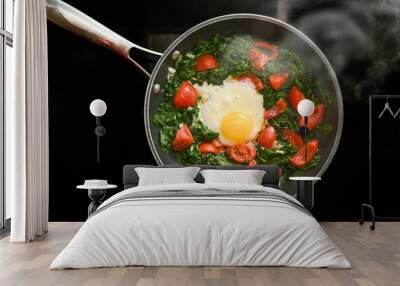 Spinach, tomatoes and fried egg in a steaming pan on a black stovetop, cooking a healthy meal for breakfast or lunch, high angle view from above, copy space Wall mural