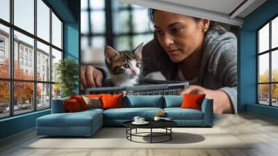 A Hispanic woman carefully handling a small kitten inside a pet carrier, symbolizing care, responsibility, and rescue. Concept of animal shelters and adoption Wall mural