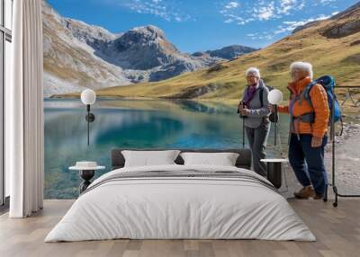 Elderly women hiking by a clear blue lake, surrounded by mountains, enjoying nature. Concept for active aging, nature appreciation, and tranquility, suitable for promoting a healthy and vibrant lifest Wall mural