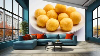 Simple yellow laddus arranged on a white plate, showcasing the traditional Indian sweet often served during Diwali and other festive occasions as a symbol of joy and prosperity Wall mural