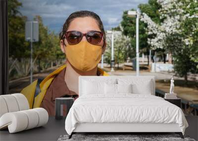 Attractive woman with face mask with a yellow jacket Wall mural