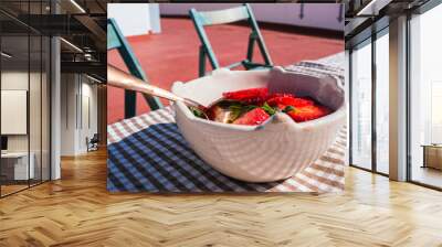 White bowl with t strawberries on a table on a terrace on a sunny day Wall mural