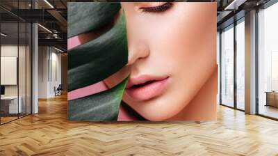 Beauty Woman with natural green palm leaf Portrait, model girl with perfect makeup, natural eyeshadows. Brunette Beautiful Fashion Model Girl Face. Skin care. Perfect Skin. On pink Background Wall mural