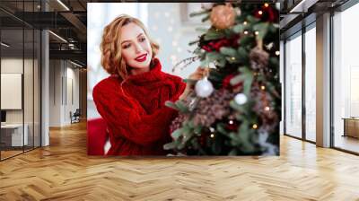 holidays, celebration and people concept - smiling woman in red sweater over christmas tree background Wall mural