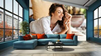 Home lifestyle woman relaxing enjoying luxury sofa on outdoor patio living room. Young female sitting on green garden terrace Wall mural