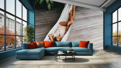 Young beautiful woman relaxing in hammock in a tropical resort Wall mural