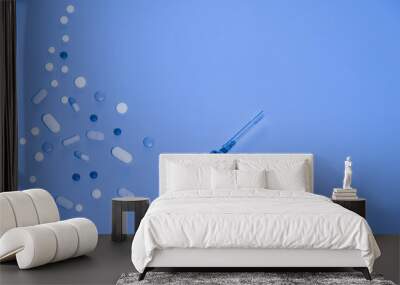 Medical blue background, syringe and many different pills copy space Wall mural