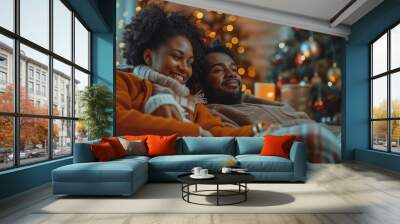 The couple relaxes in a cozy atmosphere, wrapped in blankets, surrounded by Christmas decorations and a glowing Christmas tree. Warm atmosphere and joy of communication during the holidays Wall mural