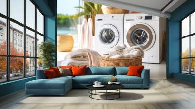 Wicker basket with clothes and towels in the laundry room against the background of a washing machine and dryer Wall mural