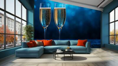 Champagne glasses filled with sparkling wine against a dark blue bokeh background Wall mural