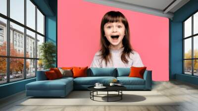 Wow. Crazy good news. Image of overjoyed excited screaming amazed little child girl standing isolated over pink background. Looking camera with open mouth.  Wall mural