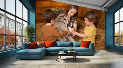 little children petting and feeding a goat. Child playing with a farm animal on sunny summer day. Kids interacting with animals. Wall mural