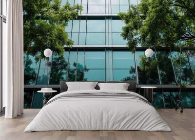 View of trees in front of a glass building against blue sky Wall mural