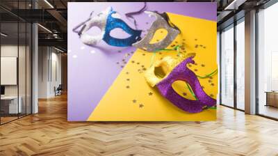 A festive, colorful group of mardi gras or carnivale mask on a yellow purple background. Venetian masks. Wall mural