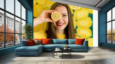 girl holding lemons in front of her eyes Wall mural