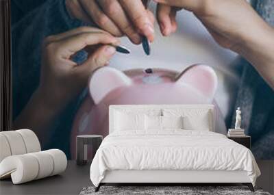 Close-up hands putting coin in happy smiling piggy bank. People saving money for household payments, bank bills, calculating monthly family budgets, making investments or strategy for retirement. Wall mural