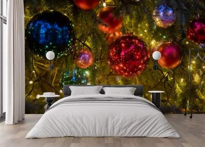 Close-up of a Christmas tree branch with decorative balls, toys and a shining garland. soft focus, background in blur. Wall mural