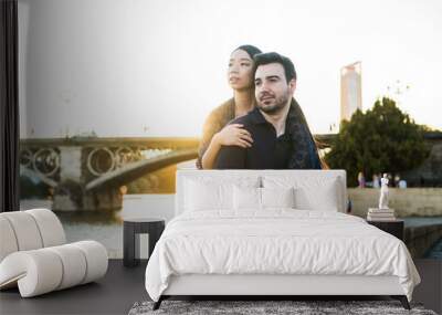 Young multiracial couple by the river with a sunset. Wall mural