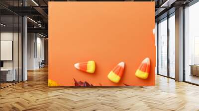 Fall-themed border with mini pumpkins, candy corn, and autumn leaves on a bright orange background. Wall mural