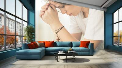 Hands folded in prayer on a Holy Bible in church concept for faith, spirituality and religion, woman praying on holy bible in the morning. Wall mural